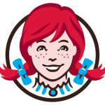 Logo of a smiling girl with red hair in pigtails, wearing blue bows, and a collar, within a circular outline.