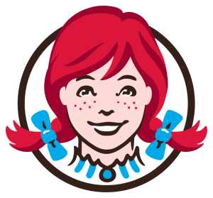 Logo of a smiling girl with red hair in pigtails, wearing blue bows, and a collar, within a circular outline.